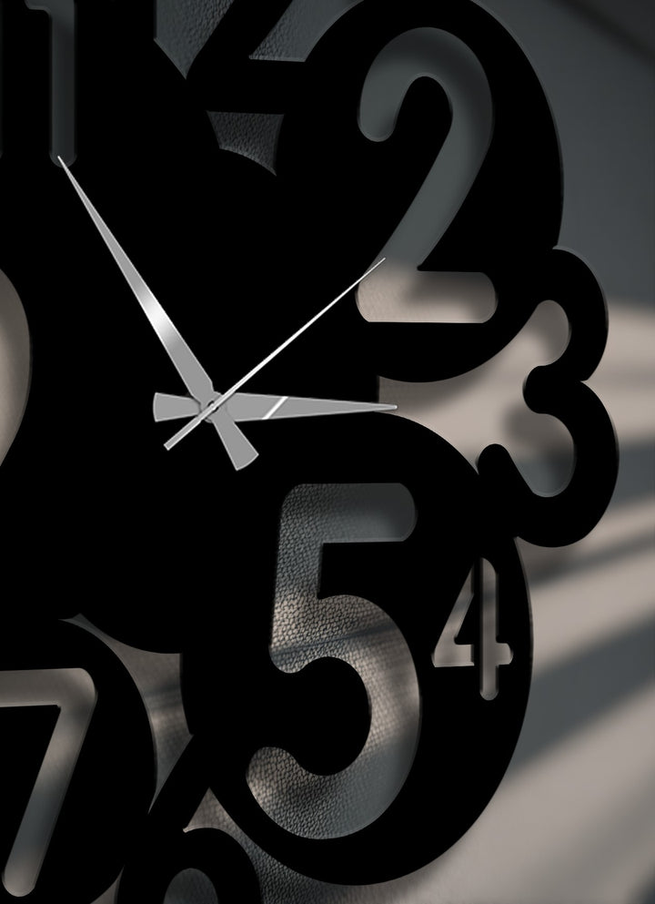 Bold, black, overlapping numbers create a striking modern abstract design on this metal wall decor, featuring sleek silver clock hands.
