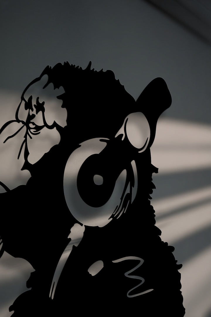 Against a muted gray background with dramatic cast shadows, the unique metal wall art of an urban monkey wearing headphones creates a striking contrast.