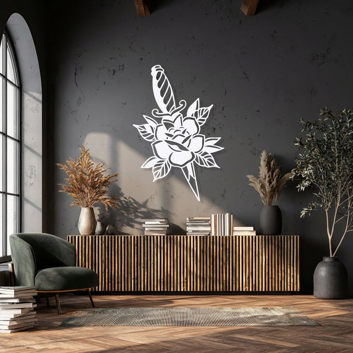 The feathery dried foliage in the beige vase softly contrasts with the striking Rose & Dagger Silhouette metal artwork on the dark wall.