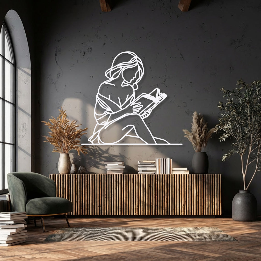 Stacked books and a plush emerald armchair dominate the foreground, complementing the elegant Quiet Reader Silhouette metal art for wall.