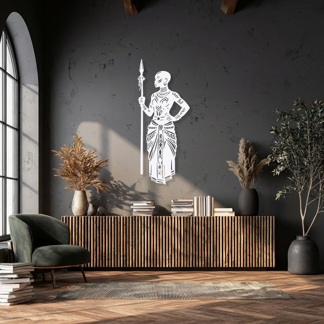 Focusing on the brightest area, a striking white metal art for wall depicts a Tribal African Warrior with a detailed spear on a dark wall.