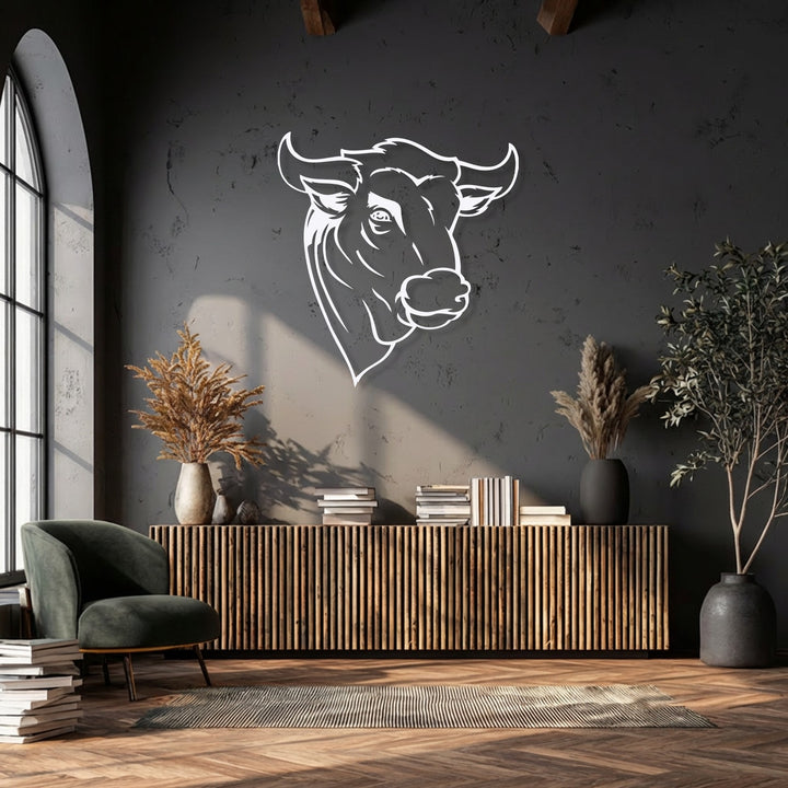 The crisp white outline of the bull head metal art for wall features defined, sleek borders, standing out elegantly against the dark textured wall.