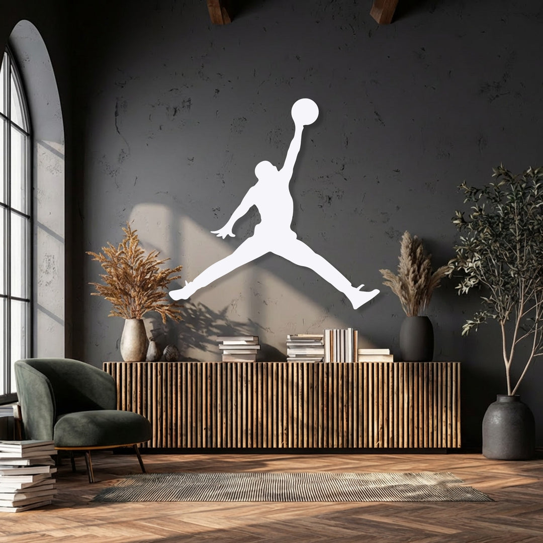 The stillness of the dramatic basketball jump player metal artwork is highlighted against a dark wall in a modern room with natural light.