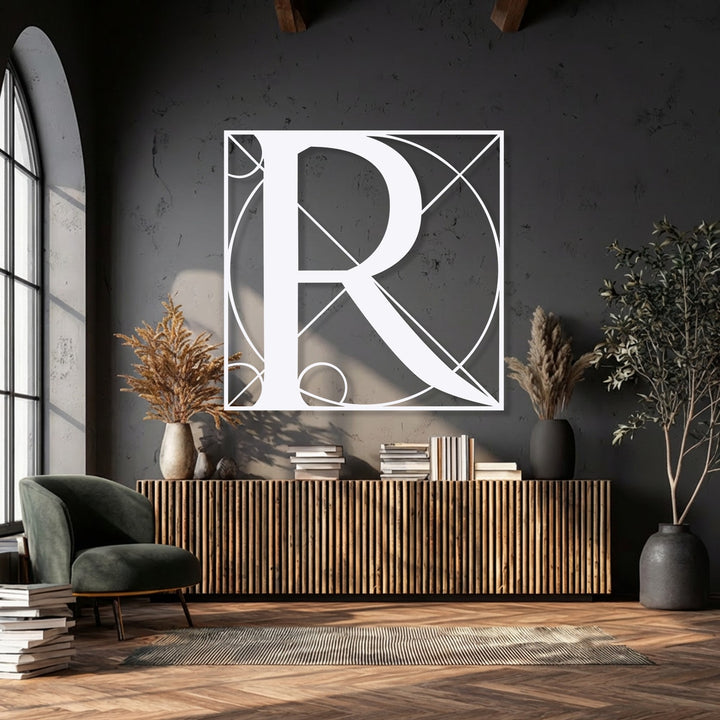 The charcoal-grey wall anchors a striking Geometric Letter R metal artwork, a modern monogram statement decor piece.