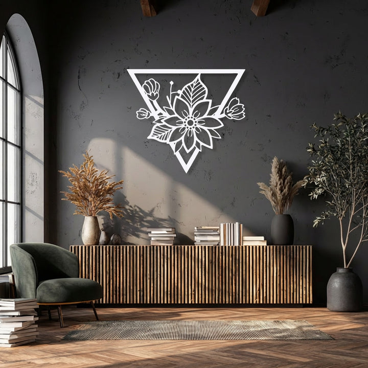 The negative space within the geometric floral blossom decorative metal art reveals the textured dark wall, highlighting its modern triangle frame.