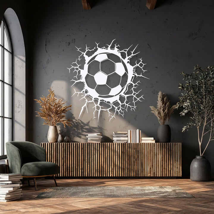 The deep grey, textured wall background stylishly showcases the unique breaking wall soccer ball metal artwork.