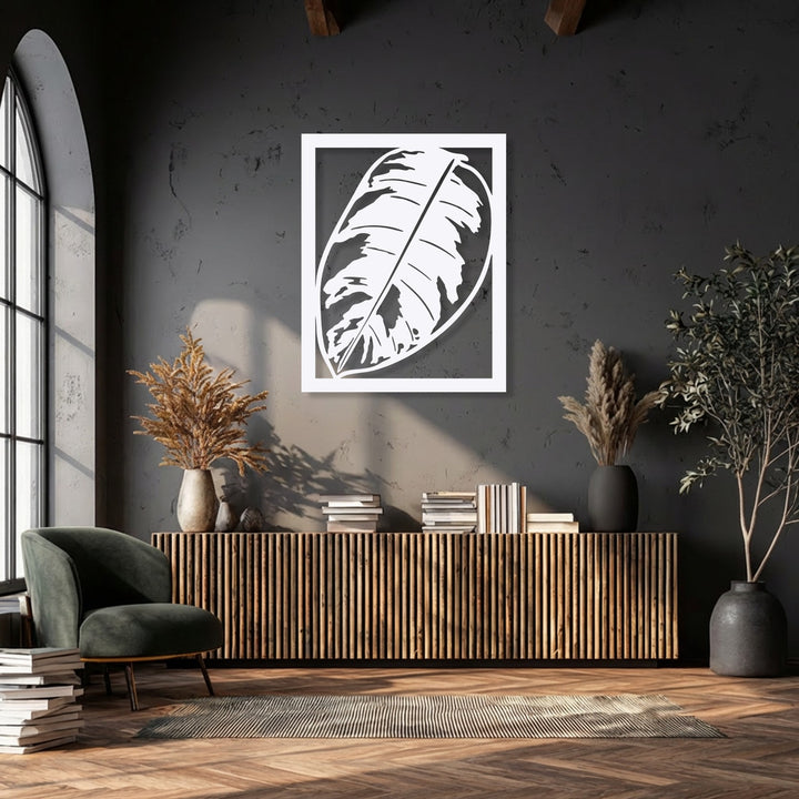 A plush dark green armchair and stacked books on a herringbone floor complement the Monstera Leaf metal decoration wall art.