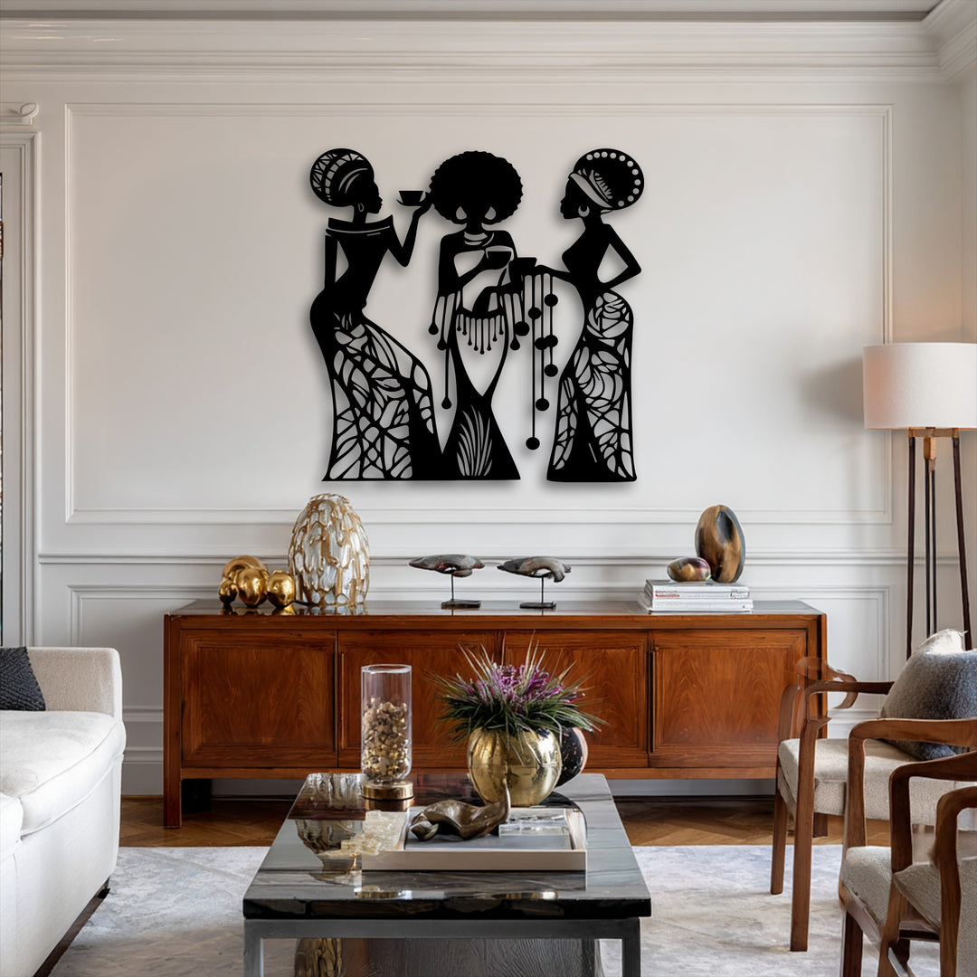 The sleek matte black finish of this unique metal wall art showcases an intricate silhouette of three African women in an elegant display.