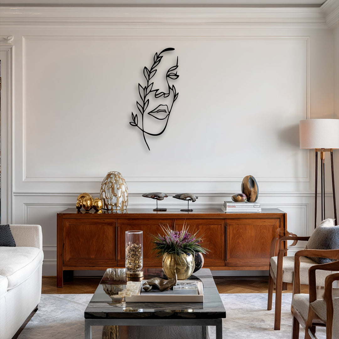A striking minimalist female line art in black metal, enhanced with botanical accents, serves as elegant metal wall decor above a rich wooden console.
