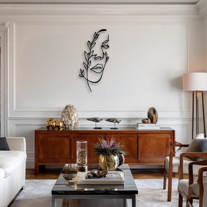 A striking minimalist female line art in black metal, enhanced with botanical accents, serves as elegant metal wall decor above a rich wooden console.