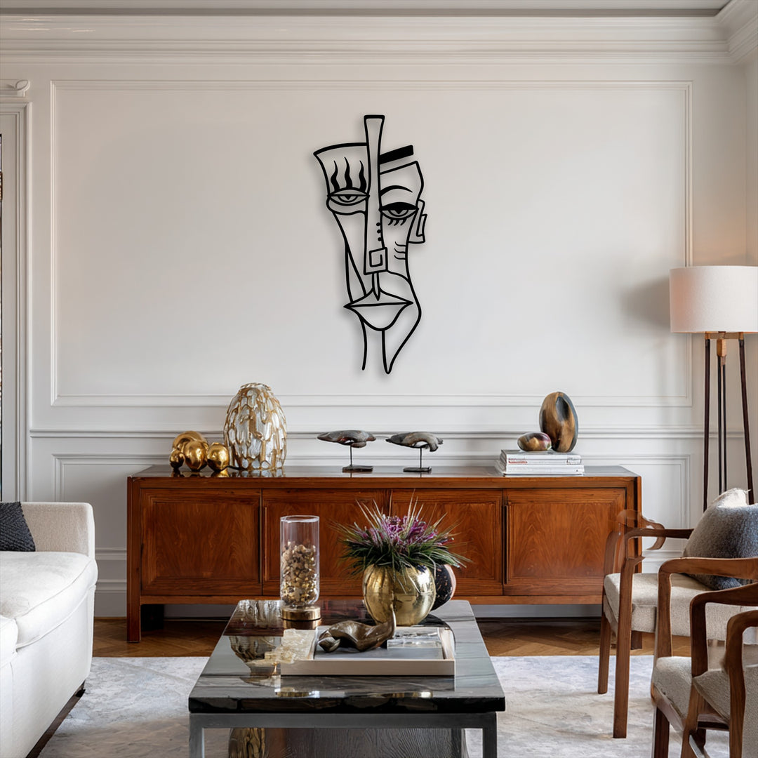The stark black abstract tribal face decorative metal art dramatically contrasts against the pristine white wall in a modern living space.