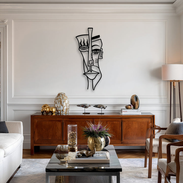 The stark black abstract tribal face decorative metal art dramatically contrasts against the pristine white wall in a modern living space.