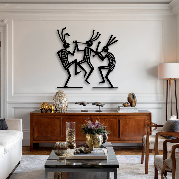 The sharp forms of the tribal dance figures metal artwork cast striking shadows against the brightly lit wall, highlighting their cultural rhythm.