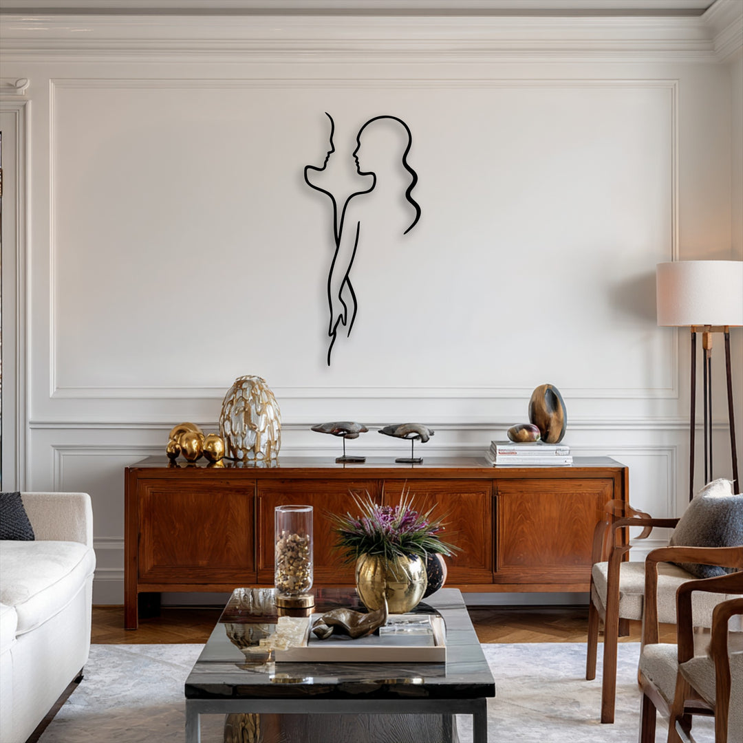 The stillness of a minimalist black metal decoration wall art depicting a couple's silhouette brings quiet elegance to a white paneled wall.