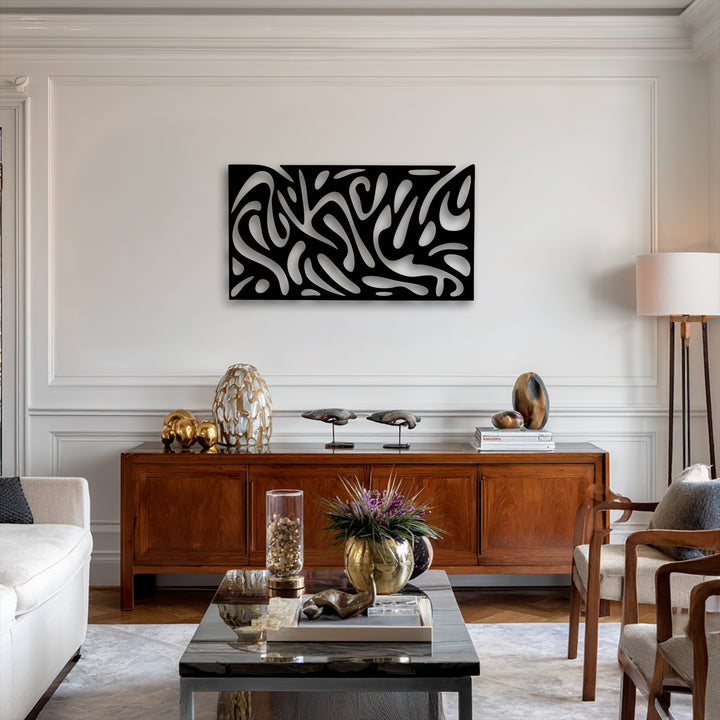 A reflective black coffee table in the foreground holds a golden vase with purple flowers, complementing the abstract metal wall decor.