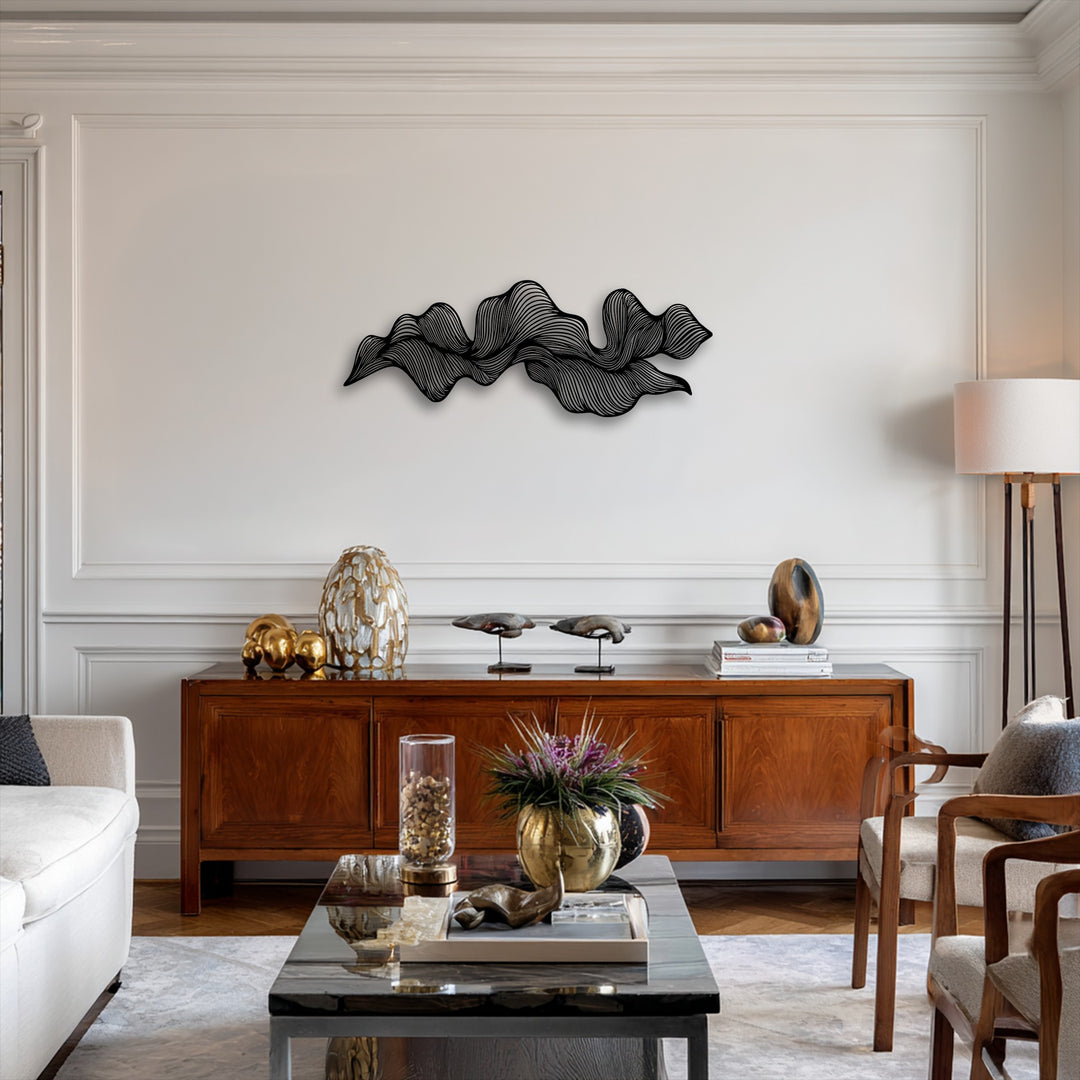 Featuring subtle color saturation, a striking black abstract wave metal wall decor piece adorns a bright white wall above a rich wooden credenza.