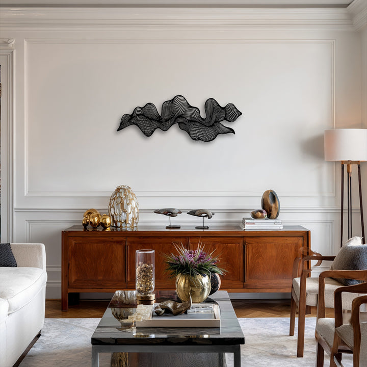 Featuring subtle color saturation, a striking black abstract wave metal wall decor piece adorns a bright white wall above a rich wooden credenza.