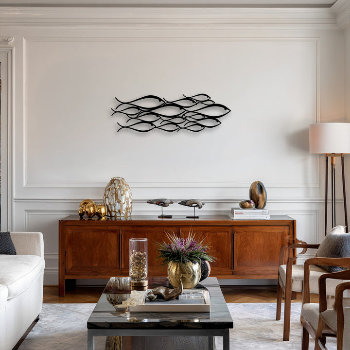 The minimalist metal wall decor, an abstract school of fish, creates a sense of depth and layers with its intricately arranged, flowing forms on the pale wall.