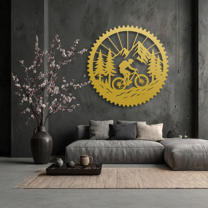 Golden metal decoration wall art vibrantly conveys movement, depicting a mountain biker on rugged trails within a striking forest and mountain scene.