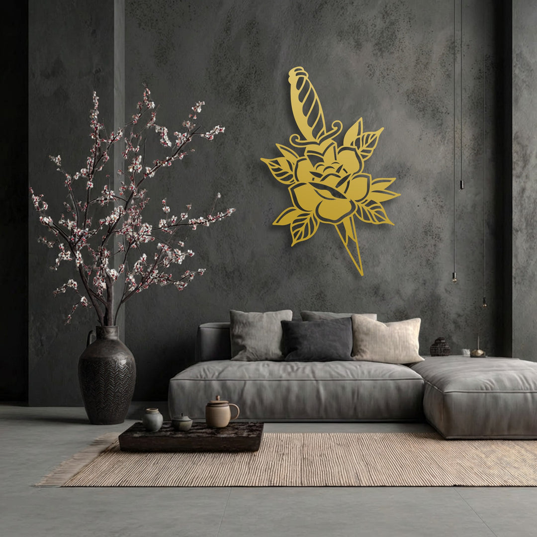 Light beautifully accentuates the gold rose and dagger metal art for wall, its bold floral silhouette casting soft shadows on the dark, textured wall.