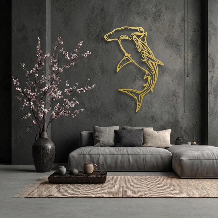 The intricate details of the stylized golden hammerhead shark unique metal wall art create a lifelike impression against the textured wall.