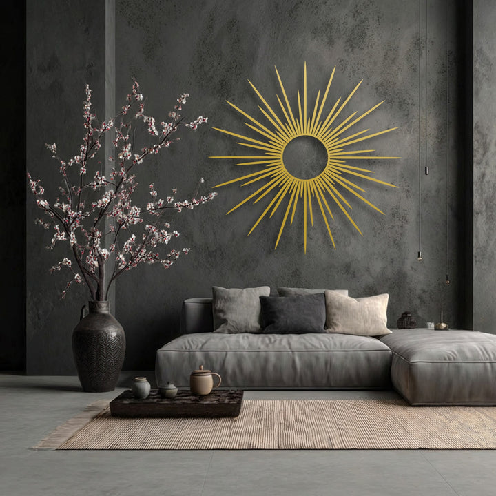 The radiant gold finish of the sunburst metal artwork glows against the dark textured wall, creating a modern abstract focal point.