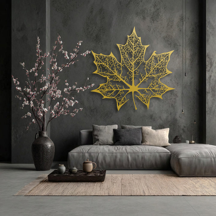 The large golden maple leaf wall art features an intricate, skeletal, geometric design, characteristic of decorative metal art.