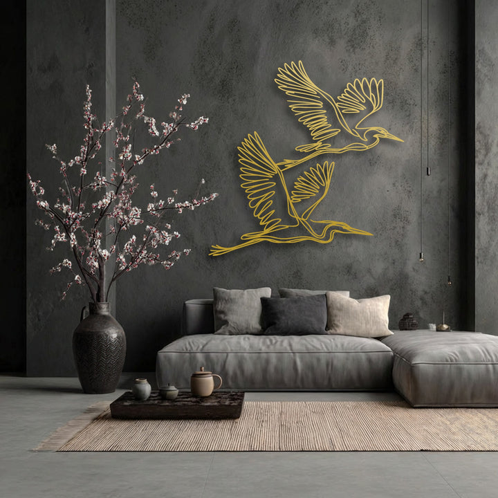 Cool color temperatures define this luxurious scene, featuring golden flying herons unique metal wall art over a plush sofa.