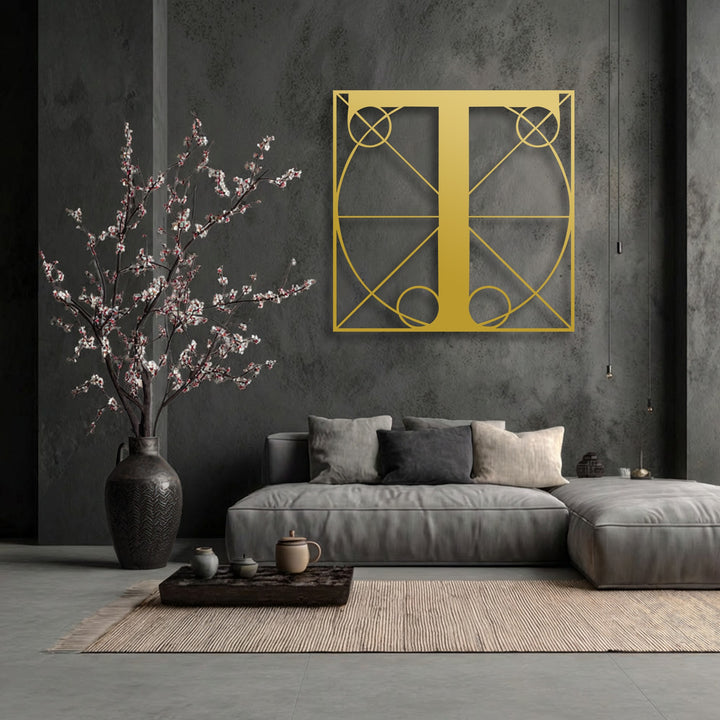 A striking golden geometric letter T, an example of unique metal wall art, dominates the dark textured wall.