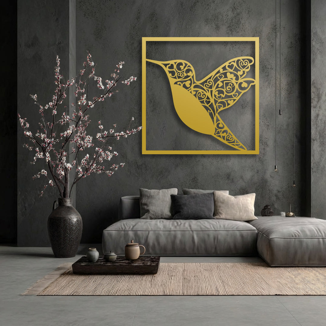 The muted color saturation of the room highlights the vibrant golden hummingbird heart metal wall decor against a dark, textured wall.