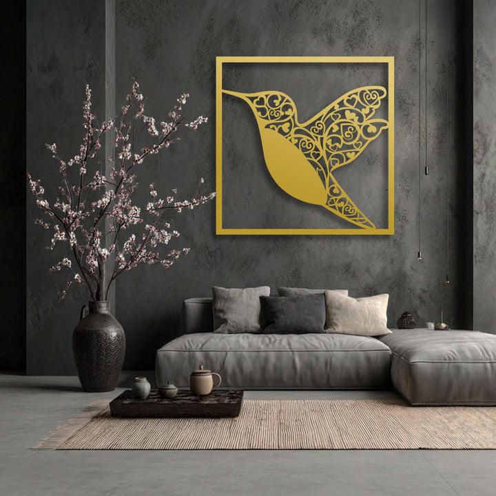 The muted color saturation of the room highlights the vibrant golden hummingbird heart metal wall decor against a dark, textured wall.