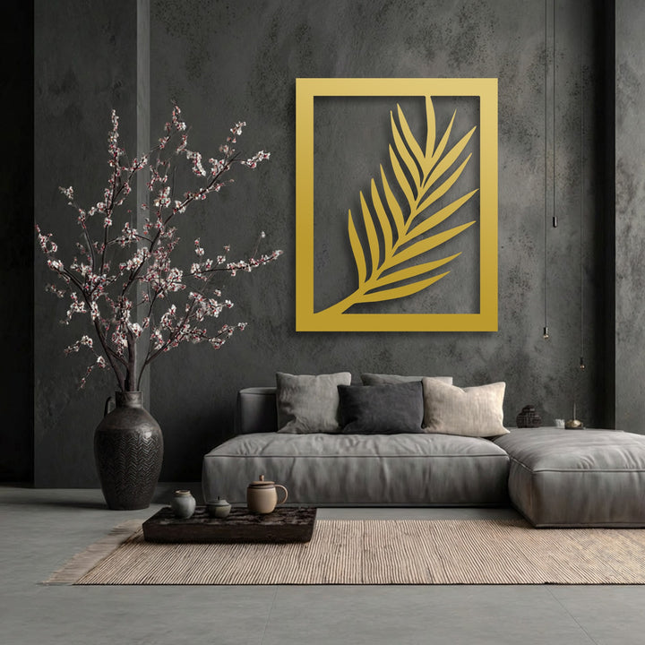 A prominent golden rectangular decoration wall art piece features a minimalist palm leaf silhouette, mounted on a dark textured wall.