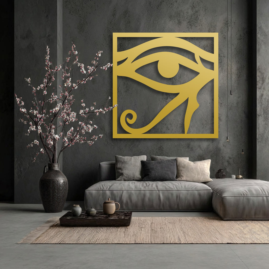 A horizontal, rectangular Eye of Horus decorative metal art piece in golden hue, casting a shadow on a dark textured wall.