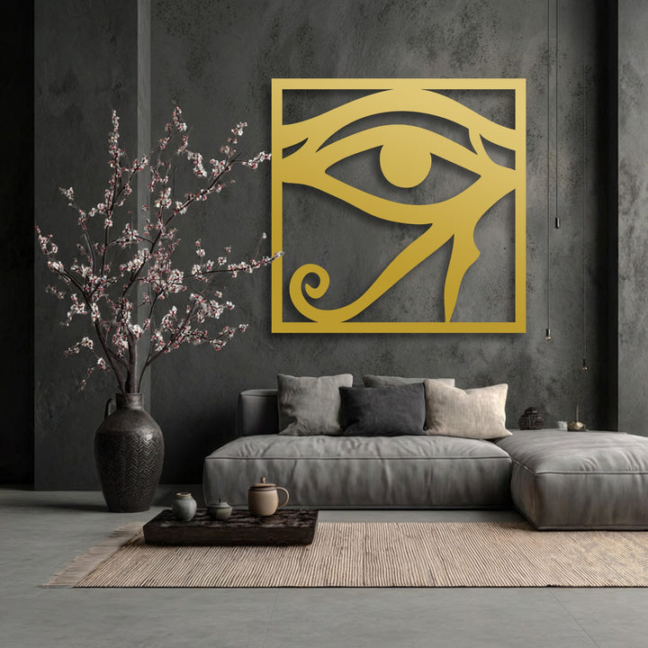 A horizontal, rectangular Eye of Horus decorative metal art piece in golden hue, casting a shadow on a dark textured wall.