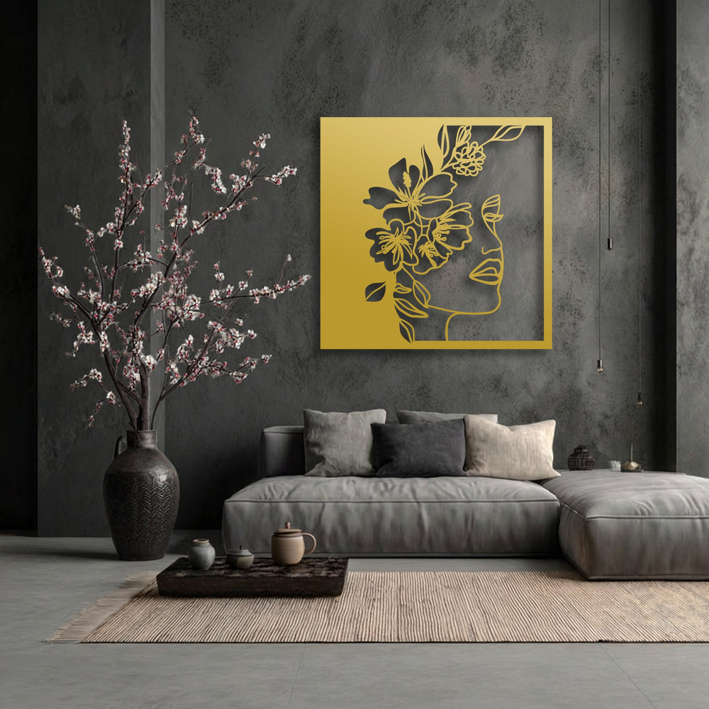 The elegant matte gold finish of the metal artwork depicts a delicate floral woman line art, adding a modern touch.