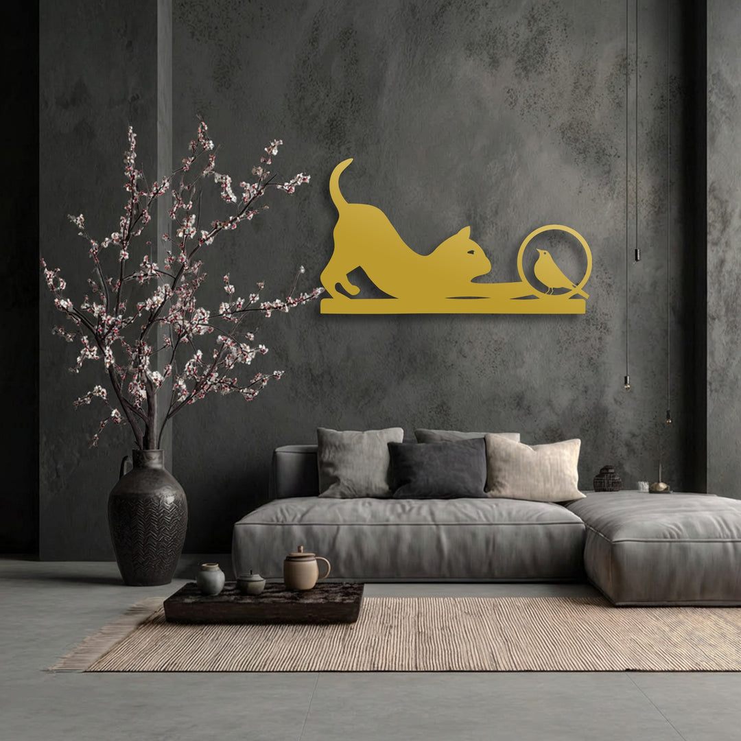 The dark wall's negative space highlights the golden silhouette of a playful cat stretching towards a curious bird, creating a unique metal wall art piece.