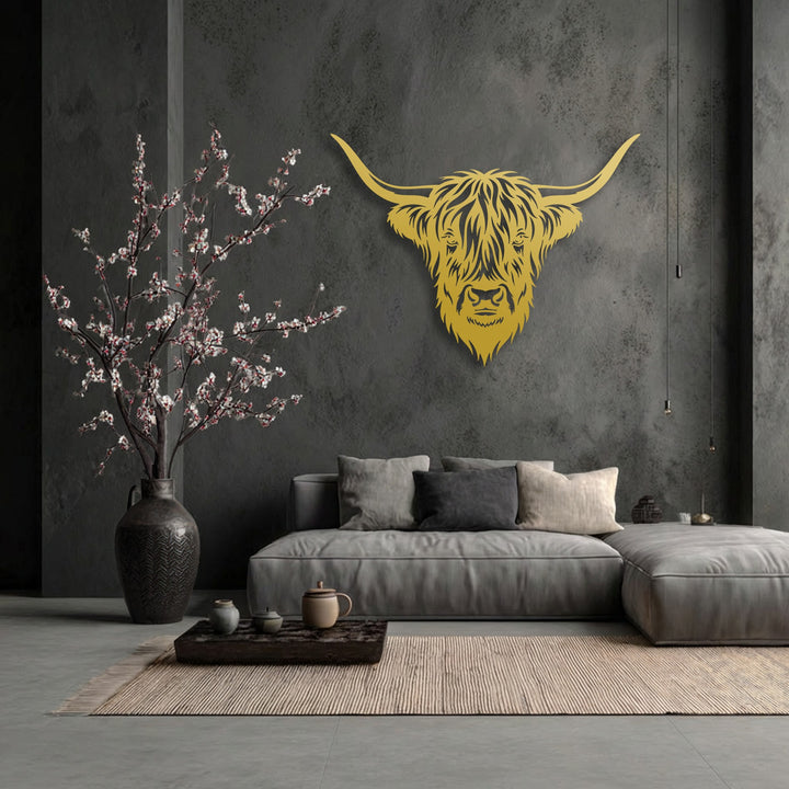 The darkest area, a charcoal gray textured wall, profoundly enhances the golden Highland Bull metal wall decor in this rustic scene.