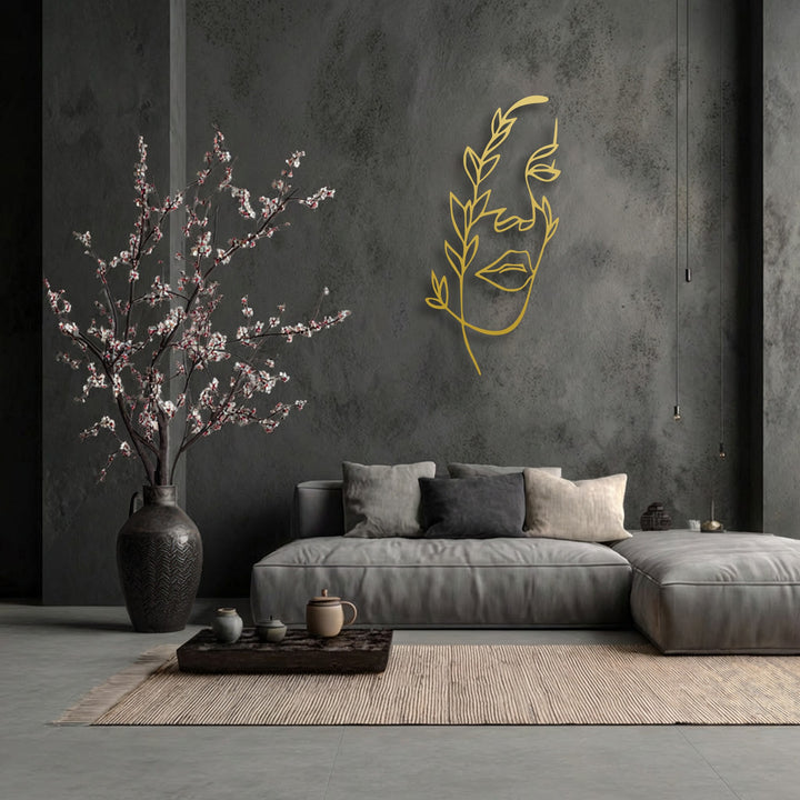 Golden minimalist female line art provides depth and layers, metal art for wall against a dark wall, with front blossoms.