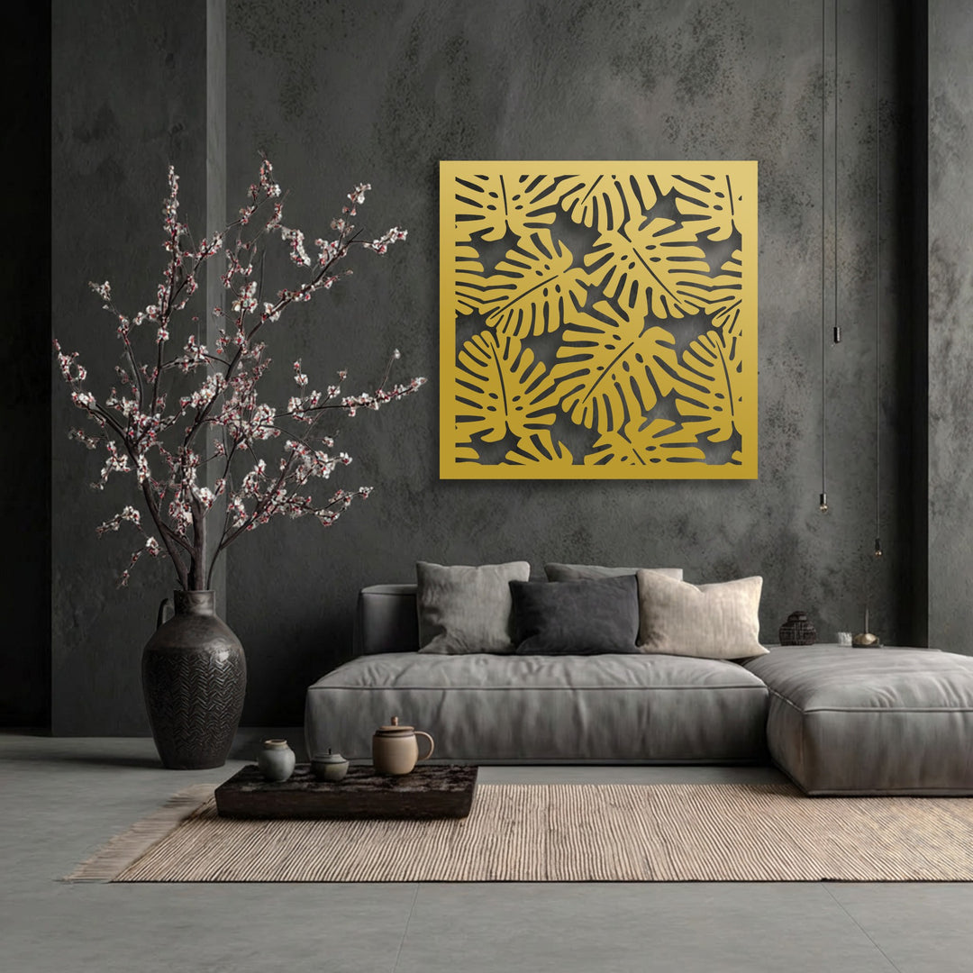 The bold transition from the dark grey wall to the bright golden decorative metal art creates a striking tropical monstera leaf pattern.