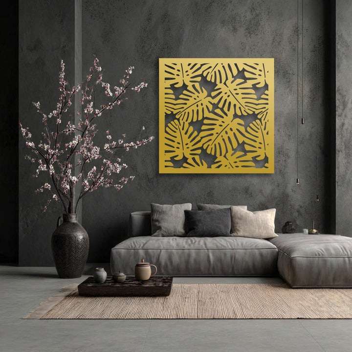 The bold transition from the dark grey wall to the bright golden decorative metal art creates a striking tropical monstera leaf pattern.