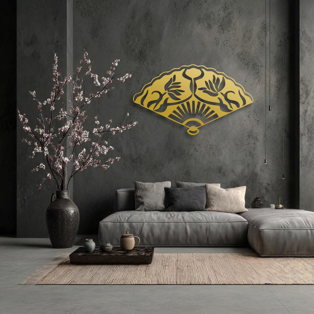 The striking golden Oriental folding fan with intricate floral motifs serves as a prominent piece of decorative metal art against the dark wall.