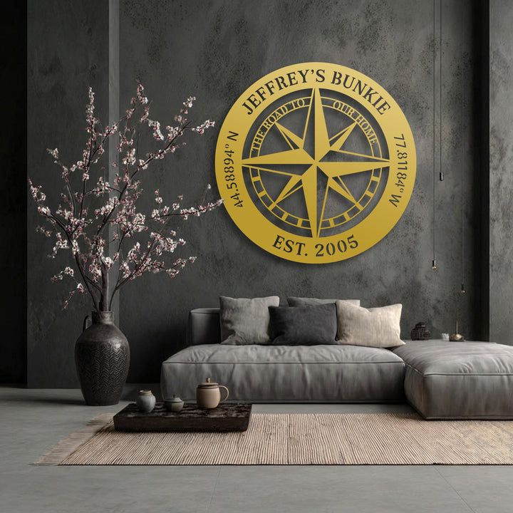 The warm color temperature of the personalized compass decorative metal art brightly contrasts with the cool, dark living space, creating an inviting glow.