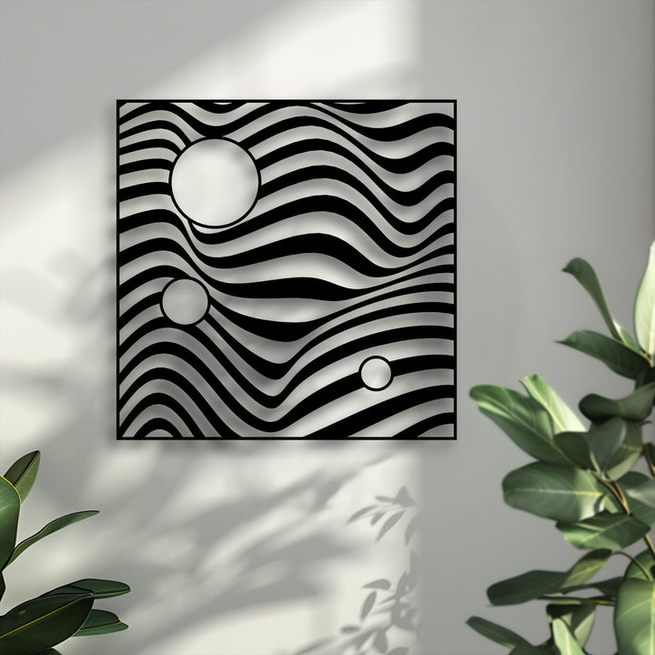 Lush green foliage softly blurs into the foreground, framing the striking abstract wave geometric metal artwork.
