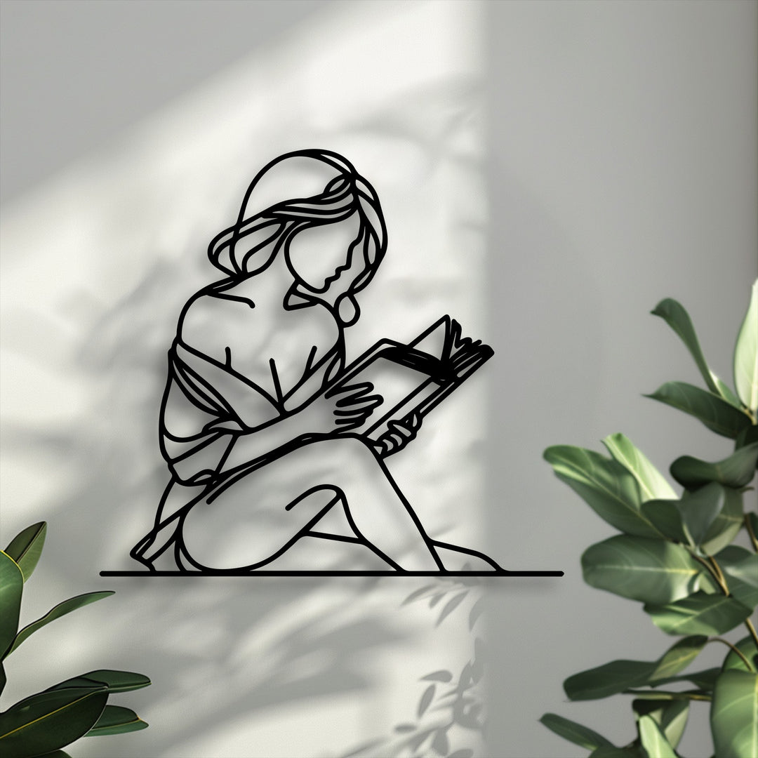 Gently dappled light and soft shadows frame the elegant metal artwork of a woman quietly reading a book.