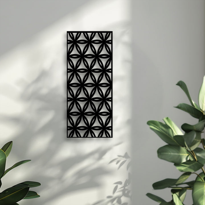With realistic detail, the unique metal wall art's geometric floral pattern casts sharp shadows on the textured wall, with hints of green plant foliage.