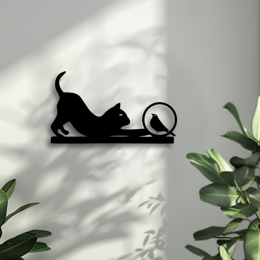 The darkest area reveals a striking decorative metal art silhouette of a playful cat stretching towards a curious bird perched within a circle.