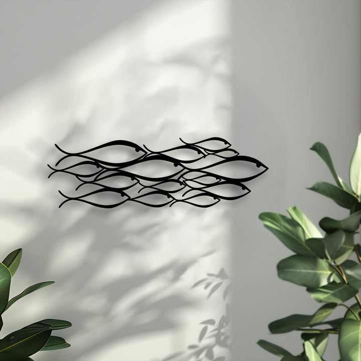 The superior material quality of this minimalist school of fish metal art for wall showcases sleek, precisely cut black metal against a bright wall.