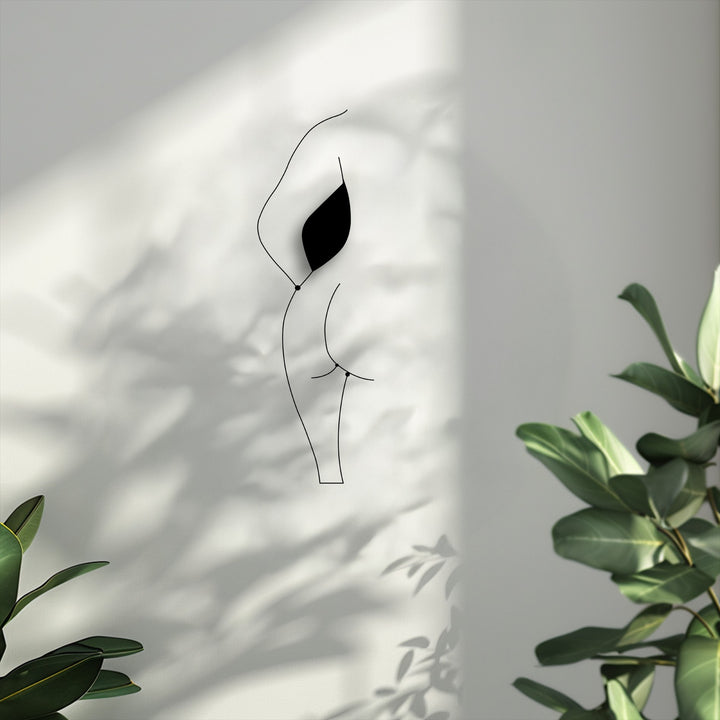 The minimalist black line art silhouette of a female figure is the focal point, serving as modern metal wall decor.