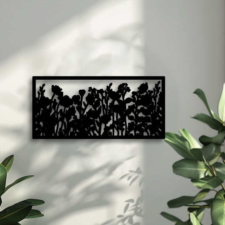 Soft, dappled shadows gently grace the wall, elegantly framing the modern wildflower silhouette metal art for wall with lush green plants.