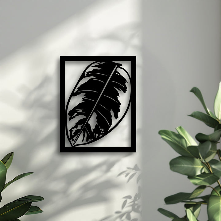 Featuring a matte black finish, this minimalist tropical monstera leaf metal wall decor casts intricate shadows on the textured wall.